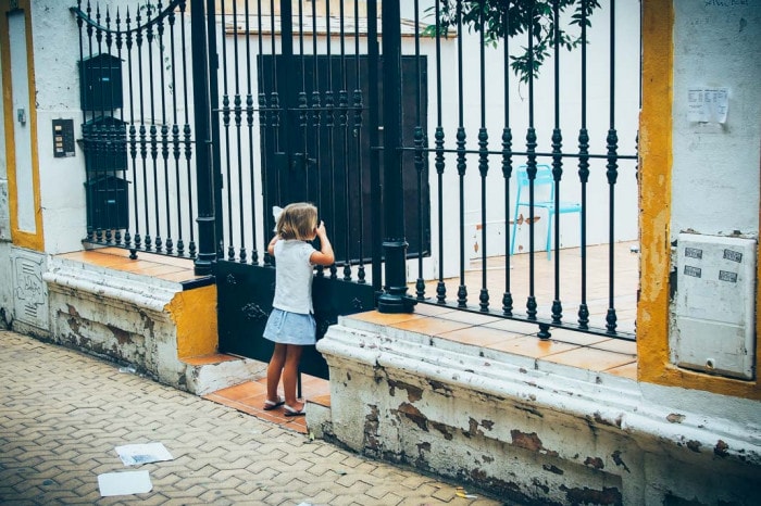 petite fille à la grille d'un portail sur la place Alameda de Hercules à seville, voyage en espagne