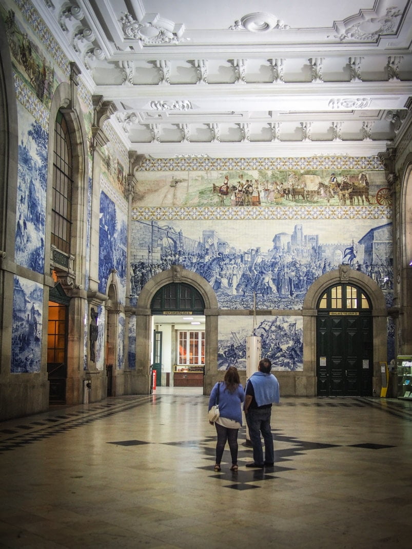 deux touristes contemplent la gare de porto et ses superbes azulejos voyage portugal